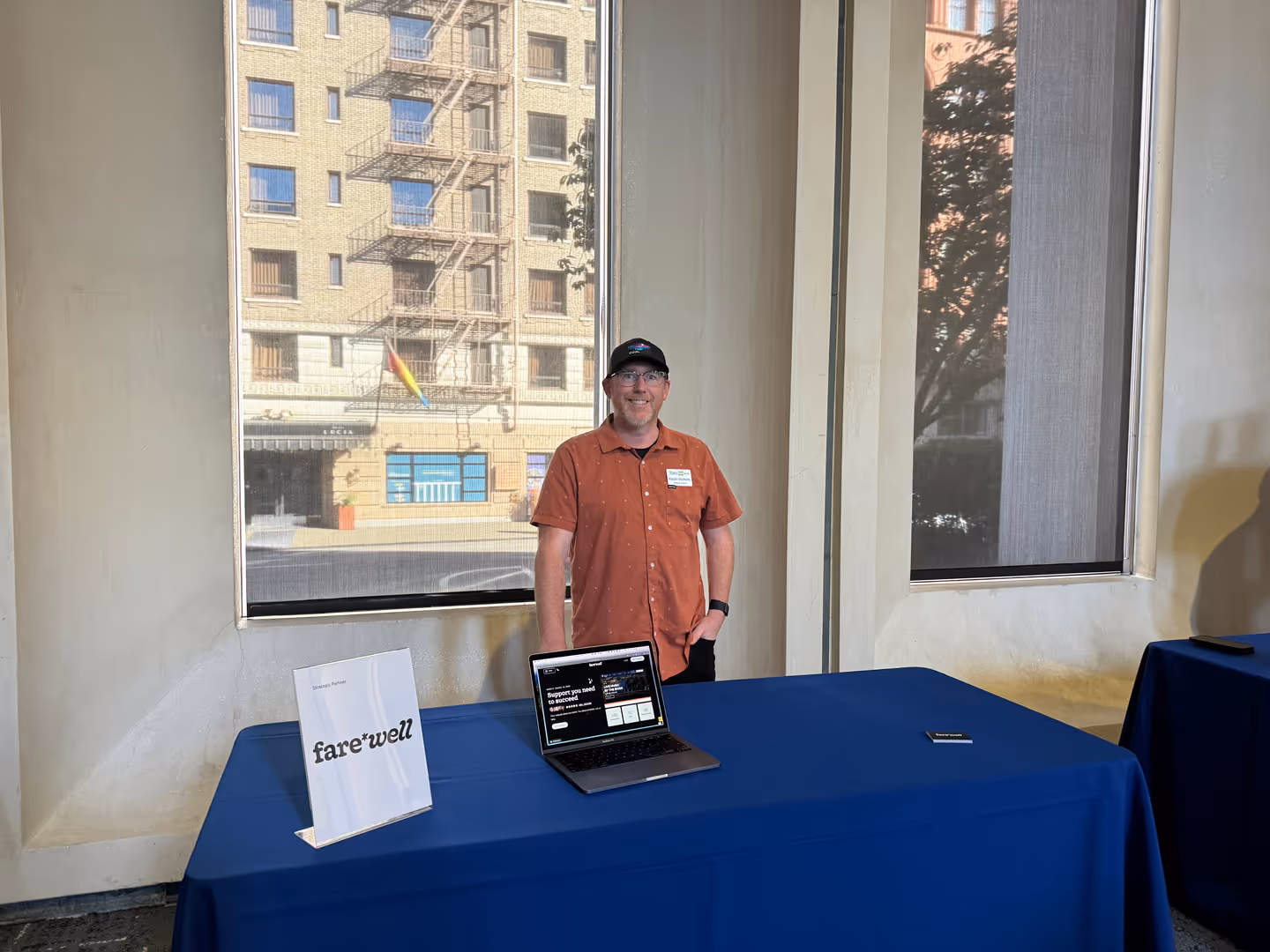 A teammate at a Farewell booth with a laptop